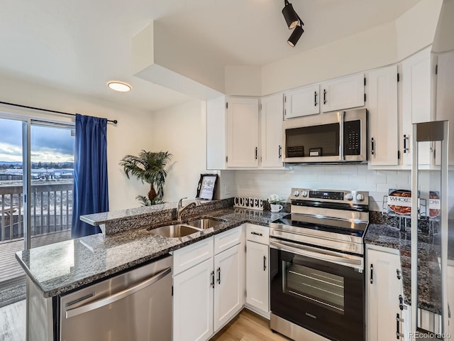 kitchen featuring stainless steel appliances, white cabinets, a sink, and a peninsula