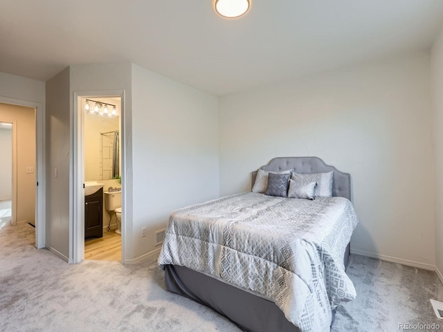 bedroom with baseboards, connected bathroom, visible vents, and light colored carpet