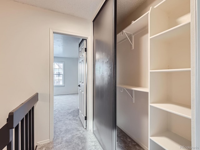 interior space featuring a textured ceiling, carpet flooring, an upstairs landing, and baseboards