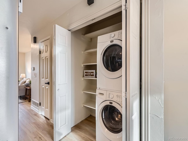 laundry area with stacked washing maching and dryer, laundry area, and light wood finished floors