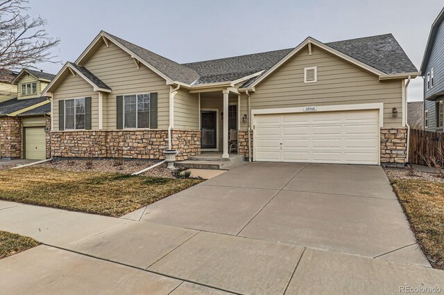 view of front of house featuring fence, driveway, a shingled roof, a garage, and stone siding