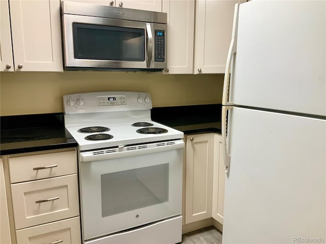 kitchen featuring white appliances, light hardwood / wood-style floors, and white cabinets