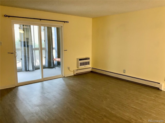 spare room with hardwood / wood-style floors, a wall mounted AC, and baseboard heating