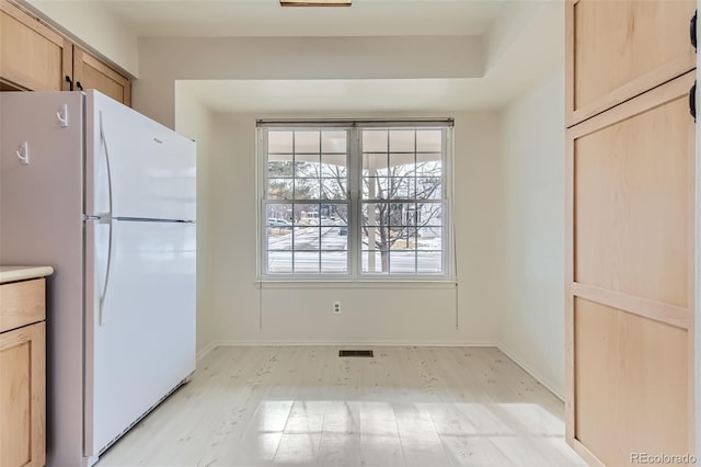 kitchen featuring white refrigerator, light hardwood / wood-style flooring, and light brown cabinets