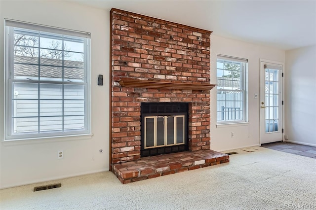 unfurnished living room featuring a brick fireplace and carpet