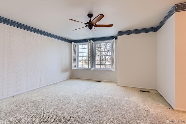 empty room with crown molding, ceiling fan, and carpet