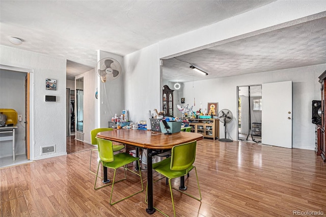 dining room featuring a textured ceiling and light hardwood / wood-style flooring