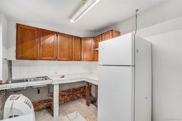 kitchen featuring backsplash, tile countertops, and white refrigerator