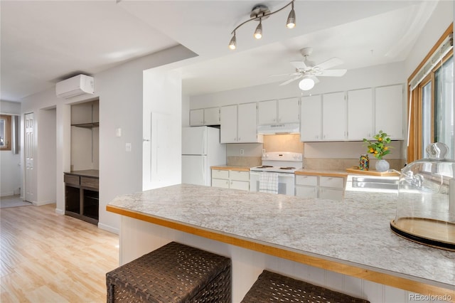 kitchen with white cabinetry, an AC wall unit, ceiling fan, kitchen peninsula, and white appliances