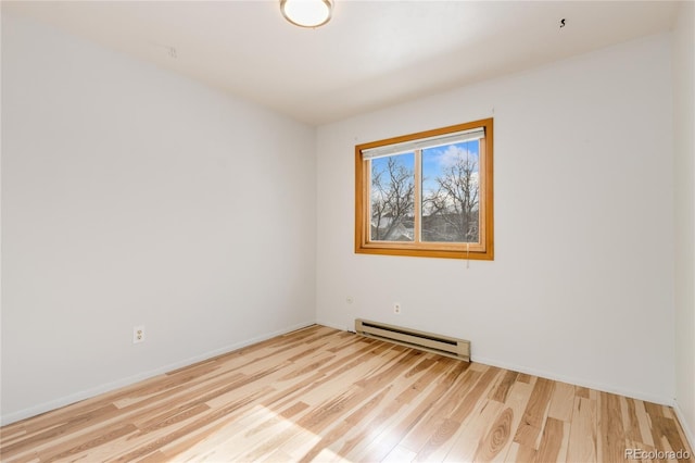 empty room featuring a baseboard heating unit and light hardwood / wood-style flooring