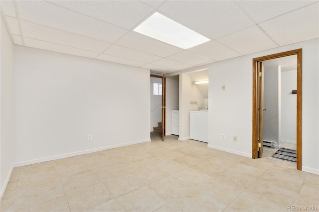 basement featuring a drop ceiling, a baseboard heating unit, and independent washer and dryer