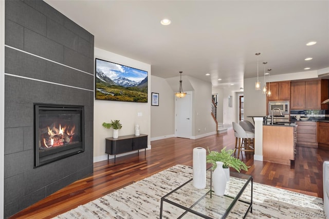 living room featuring dark wood-type flooring, a fireplace, and recessed lighting