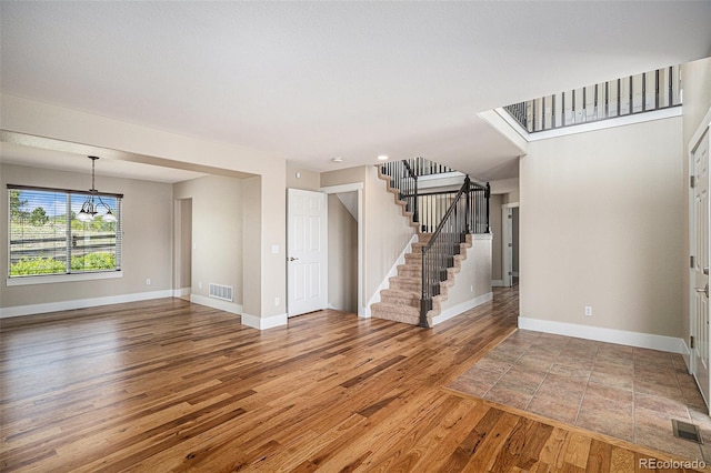 unfurnished living room featuring wood finished floors, a chandelier, and baseboards