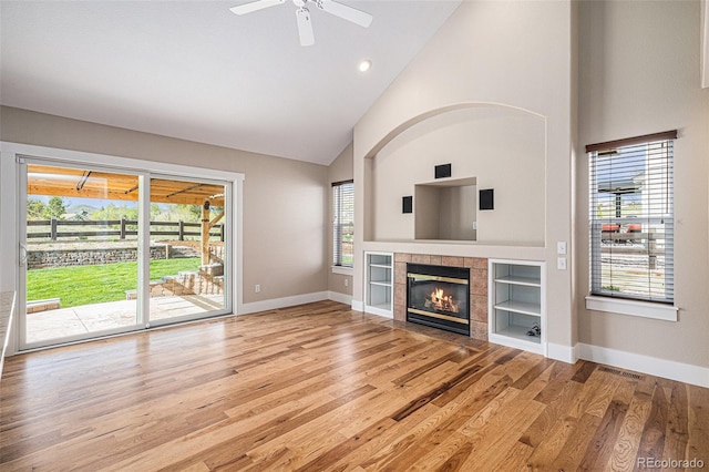 unfurnished living room featuring wood finished floors, a fireplace, high vaulted ceiling, a ceiling fan, and baseboards