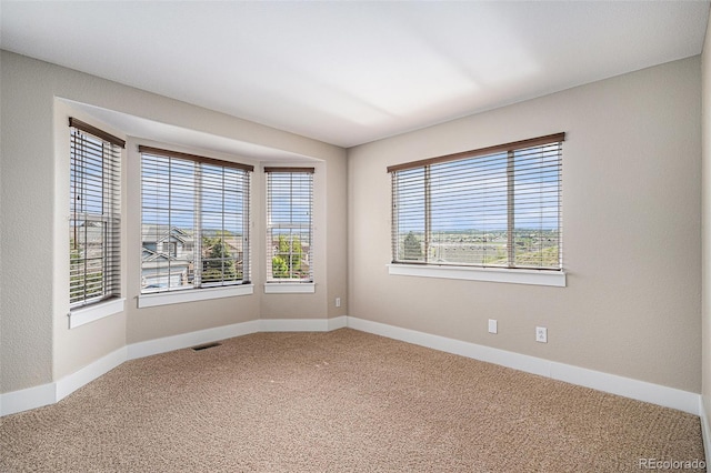 carpeted empty room featuring baseboards