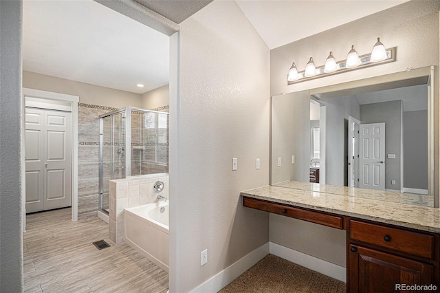 full bathroom featuring a bath, a stall shower, vanity, baseboards, and a textured wall
