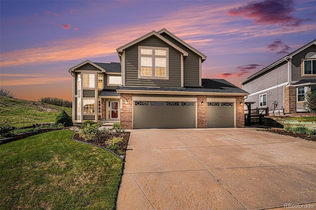 traditional-style home with brick siding, driveway, a lawn, a garage, and a shingled roof