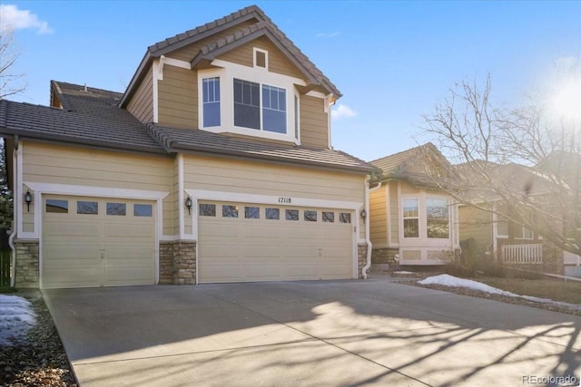 craftsman inspired home featuring a garage, driveway, and stone siding