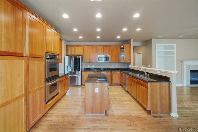 kitchen featuring dark stone countertops, a center island, a peninsula, stainless steel appliances, and a sink