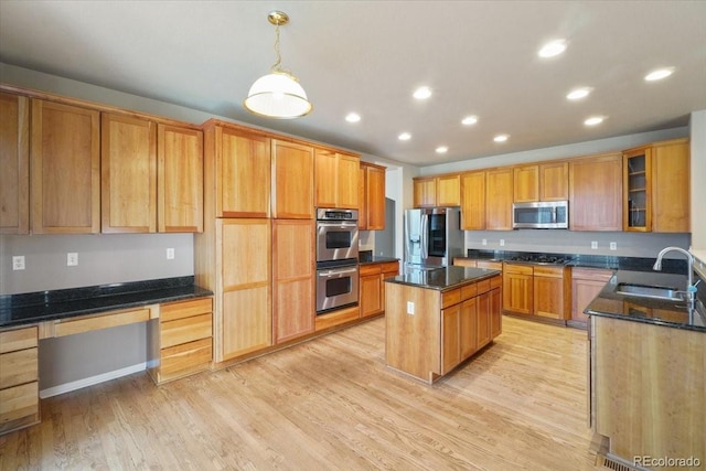 kitchen featuring a center island, stainless steel appliances, light wood-style floors, built in desk, and a sink