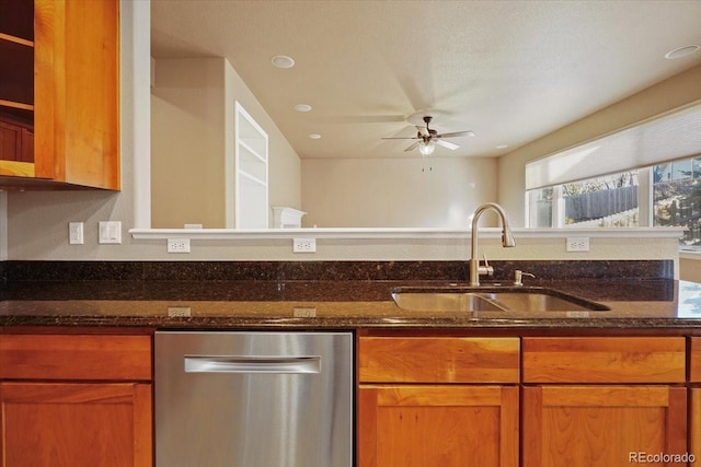 kitchen featuring dishwasher, dark stone countertops, a ceiling fan, and a sink