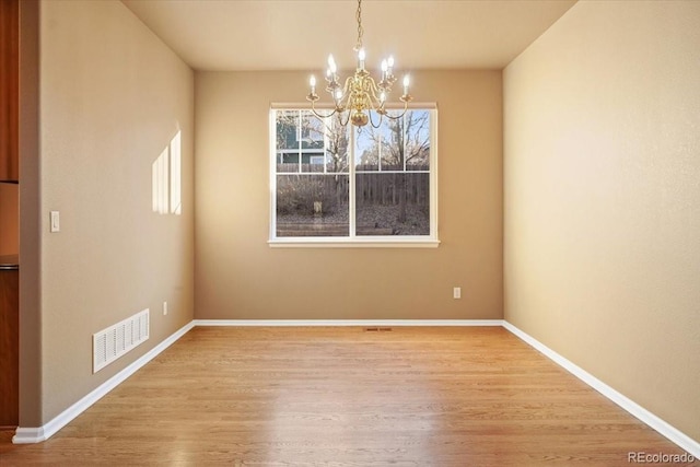 unfurnished dining area featuring visible vents, a notable chandelier, baseboards, and wood finished floors