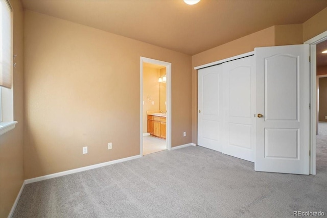 unfurnished bedroom featuring carpet floors, a closet, baseboards, and ensuite bathroom