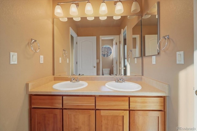 bathroom with double vanity, a sink, and toilet