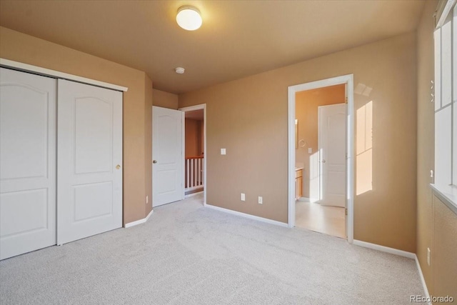 unfurnished bedroom featuring a closet, light colored carpet, and baseboards