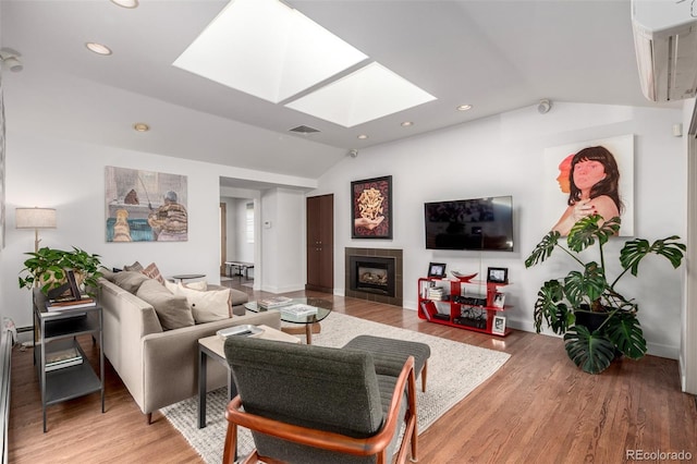 living room with lofted ceiling with skylight, visible vents, light wood finished floors, and a tiled fireplace