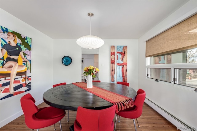 dining space featuring baseboards, baseboard heating, and wood finished floors