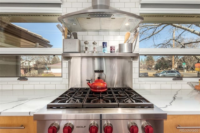 kitchen featuring range hood, light stone counters, range, and decorative backsplash