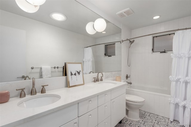 bathroom featuring tiled shower / bath, double vanity, a sink, and toilet