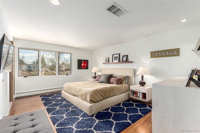 bedroom featuring a baseboard radiator, visible vents, recessed lighting, and wood finished floors