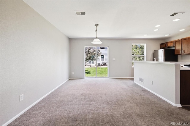 19209 E 58th Ave Unit C, Denver, CO 80249 - kitchen featuring freestanding refrigerator, light colored carpet, decorative light fixtures, light countertops, and recessed lighting