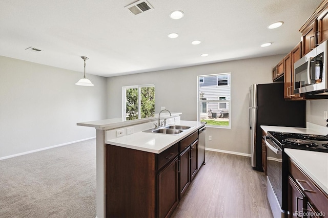 19209 E 58th Ave Unit C, Denver, CO 80249 - kitchen featuring appliances with stainless steel finishes, a kitchen island with sink, light countertops, recessed lighting, and decorative light fixtures