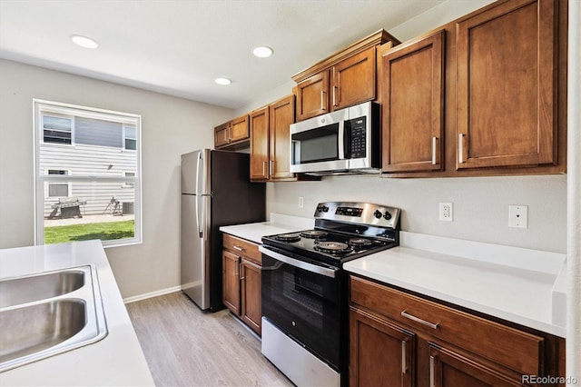 19209 E 58th Ave Unit C, Denver, CO 80249 - kitchen featuring appliances with stainless steel finishes, light wood-style flooring, light countertops, brown cabinets, and recessed lighting