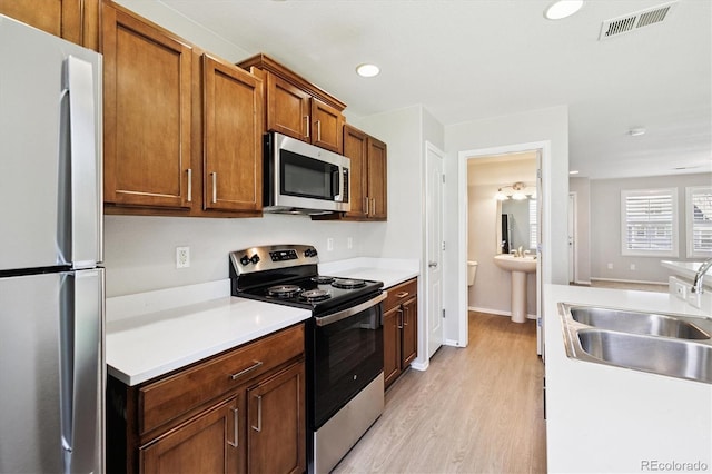 19209 E 58th Ave Unit C, Denver, CO 80249 - kitchen with stainless steel appliances, light countertops, light wood finished floors, recessed lighting, and brown cabinetry