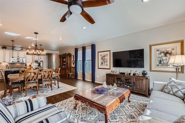 living room featuring ceiling fan with notable chandelier and dark hardwood / wood-style floors