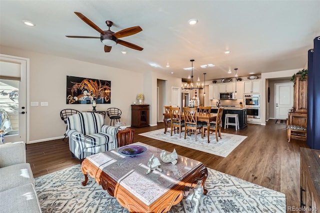 living room featuring ceiling fan with notable chandelier and dark hardwood / wood-style flooring