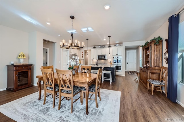 dining area with dark wood-type flooring and a notable chandelier