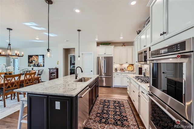 kitchen with pendant lighting, white cabinetry, an island with sink, and appliances with stainless steel finishes