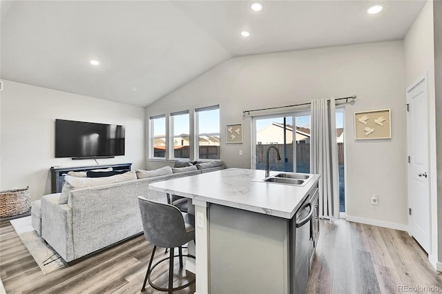 kitchen featuring vaulted ceiling, sink, a breakfast bar area, a kitchen island with sink, and light hardwood / wood-style flooring