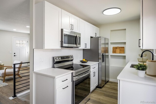 kitchen featuring light countertops, appliances with stainless steel finishes, a sink, and wood finished floors