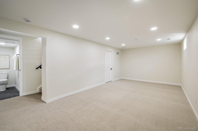 below grade area featuring light colored carpet, recessed lighting, baseboards, and stairway