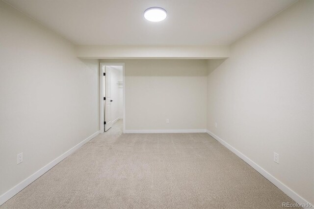 basement featuring baseboards and light carpet