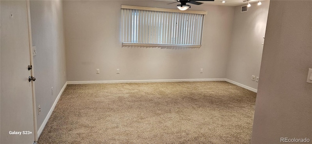 carpeted empty room with baseboards, visible vents, and a ceiling fan