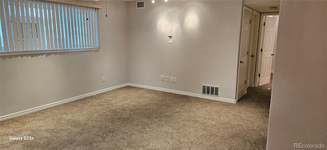 carpeted spare room featuring visible vents and baseboards