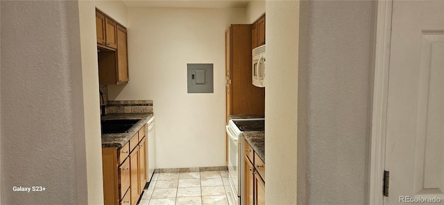 kitchen with brown cabinetry, white appliances, electric panel, and baseboards