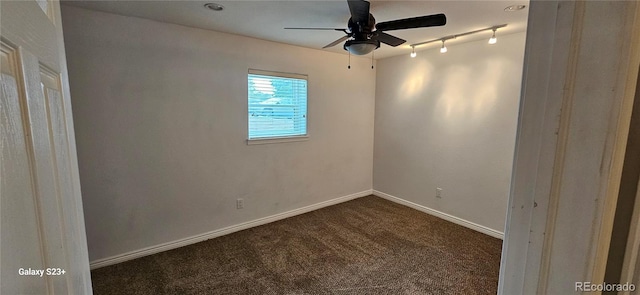 spare room featuring ceiling fan, dark colored carpet, rail lighting, and baseboards